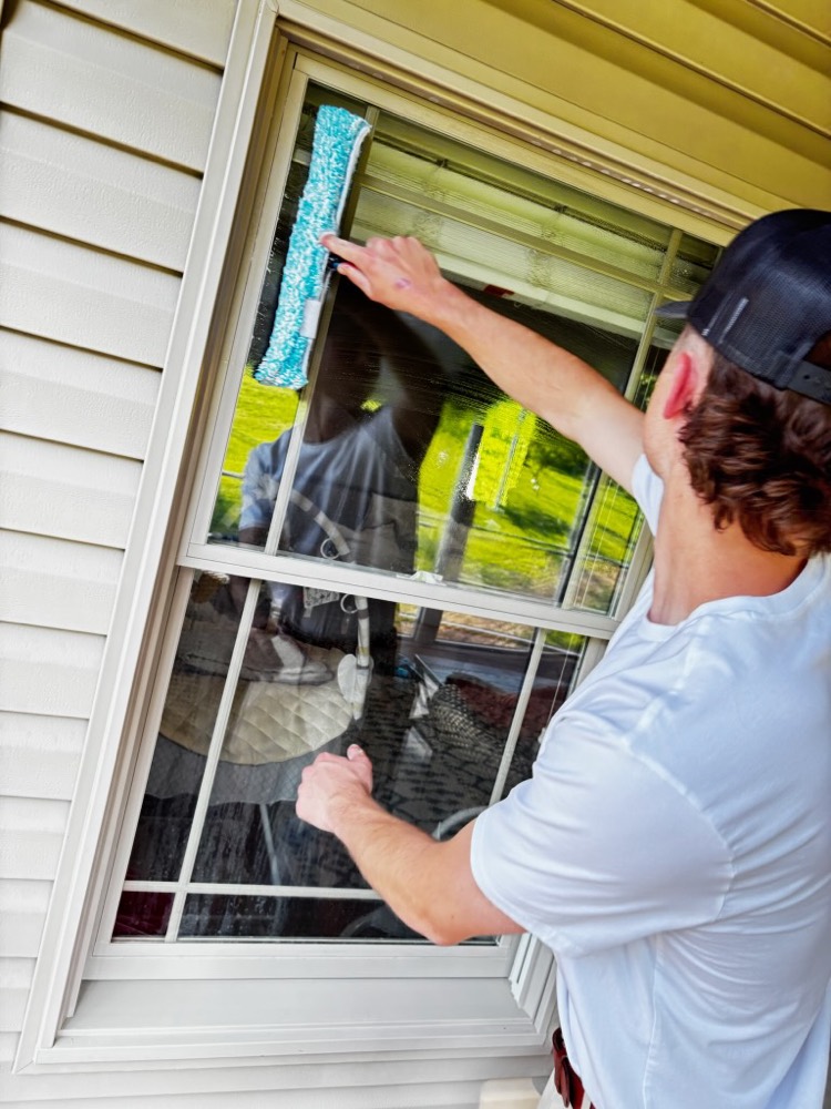 Technician cleaning an exterior window with a microfiber scrubber